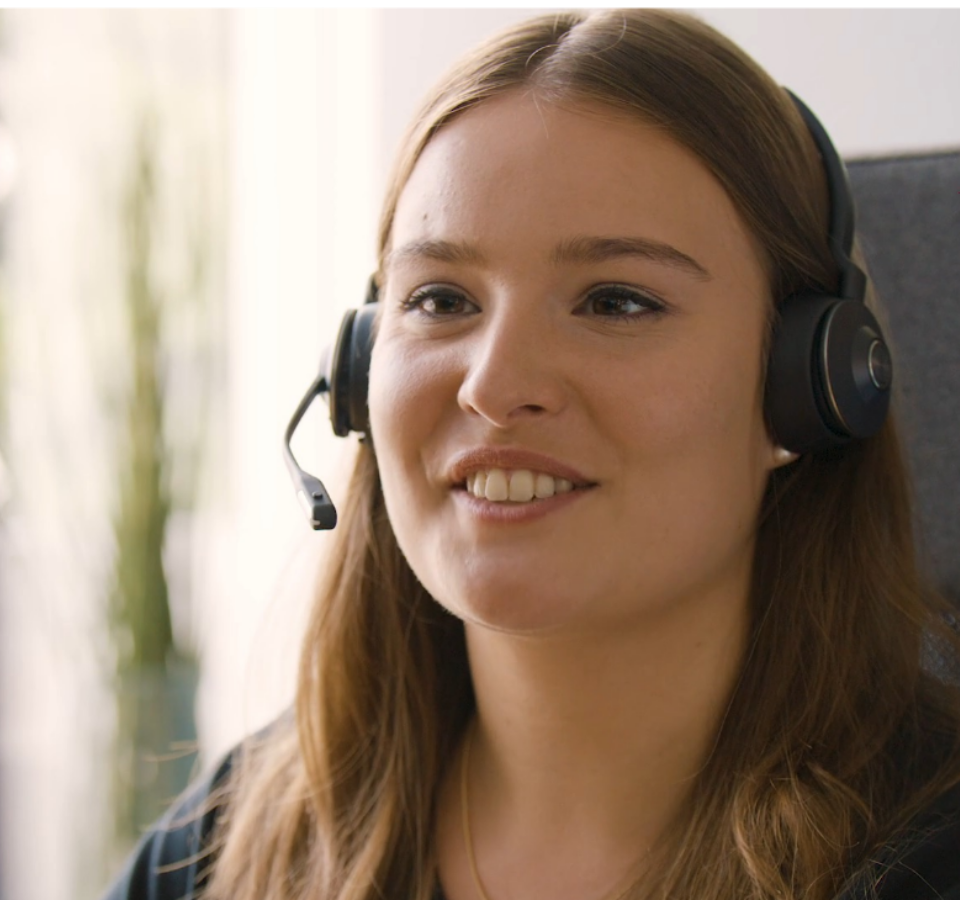 A Custom Medical employee wearing a headset and smiles.