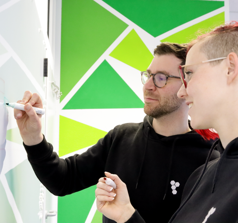 An employee and a co-worker develop a roadmap on a whiteboard.